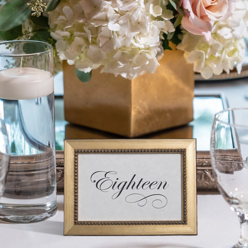 A dinner table with a gold Versailles Beaded Table number Frame